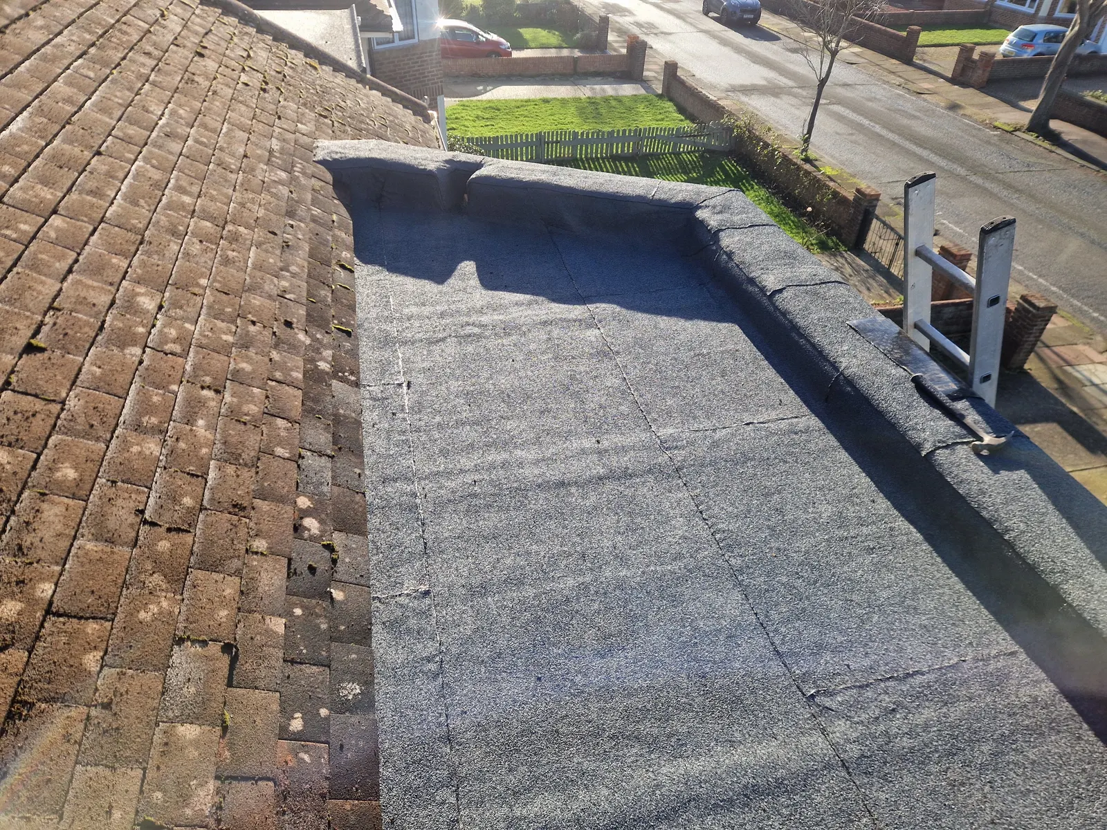 A felt flat roof finished up against a tiled roof slope