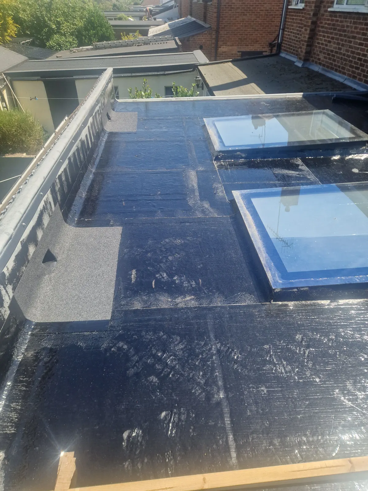 Work in progress by LDR Roofing: the underlayer bonded down around two roof lights, before the cap sheet