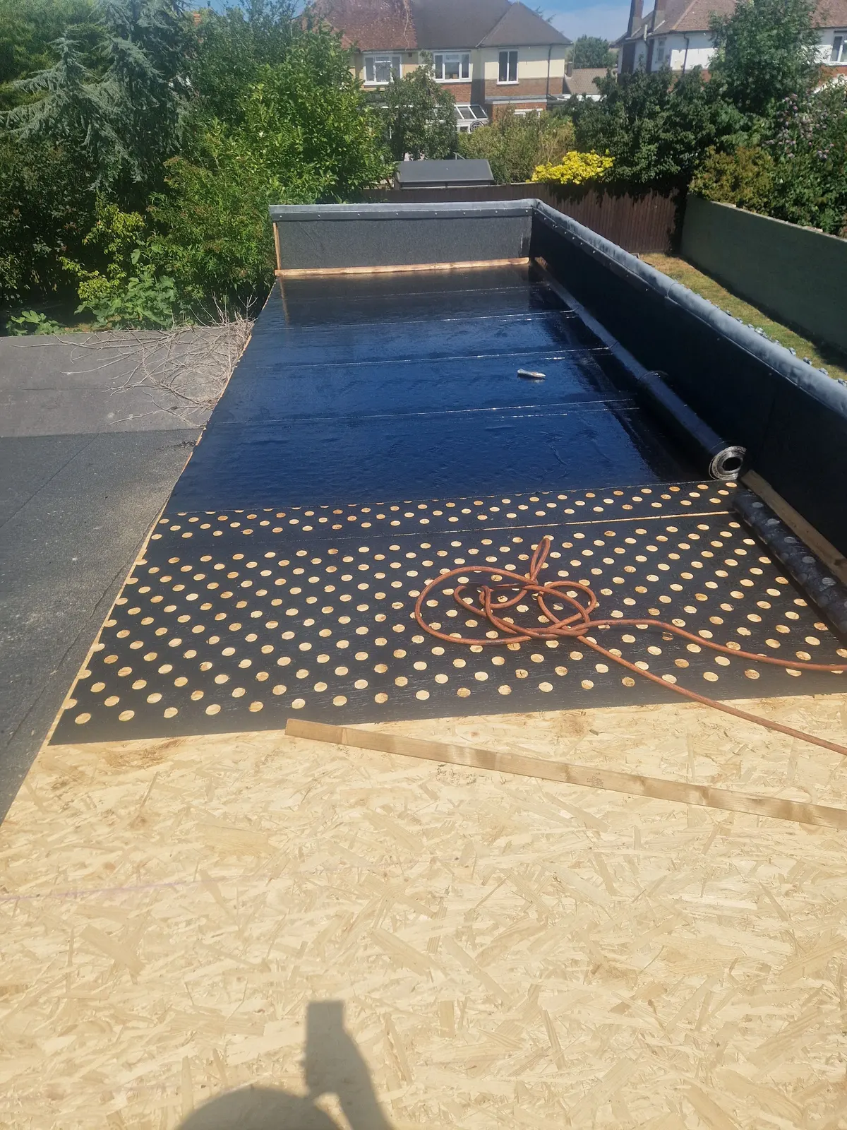 Work in progress by LDR Roofing: a timber deck with a perforated base layer going down on a flat roof