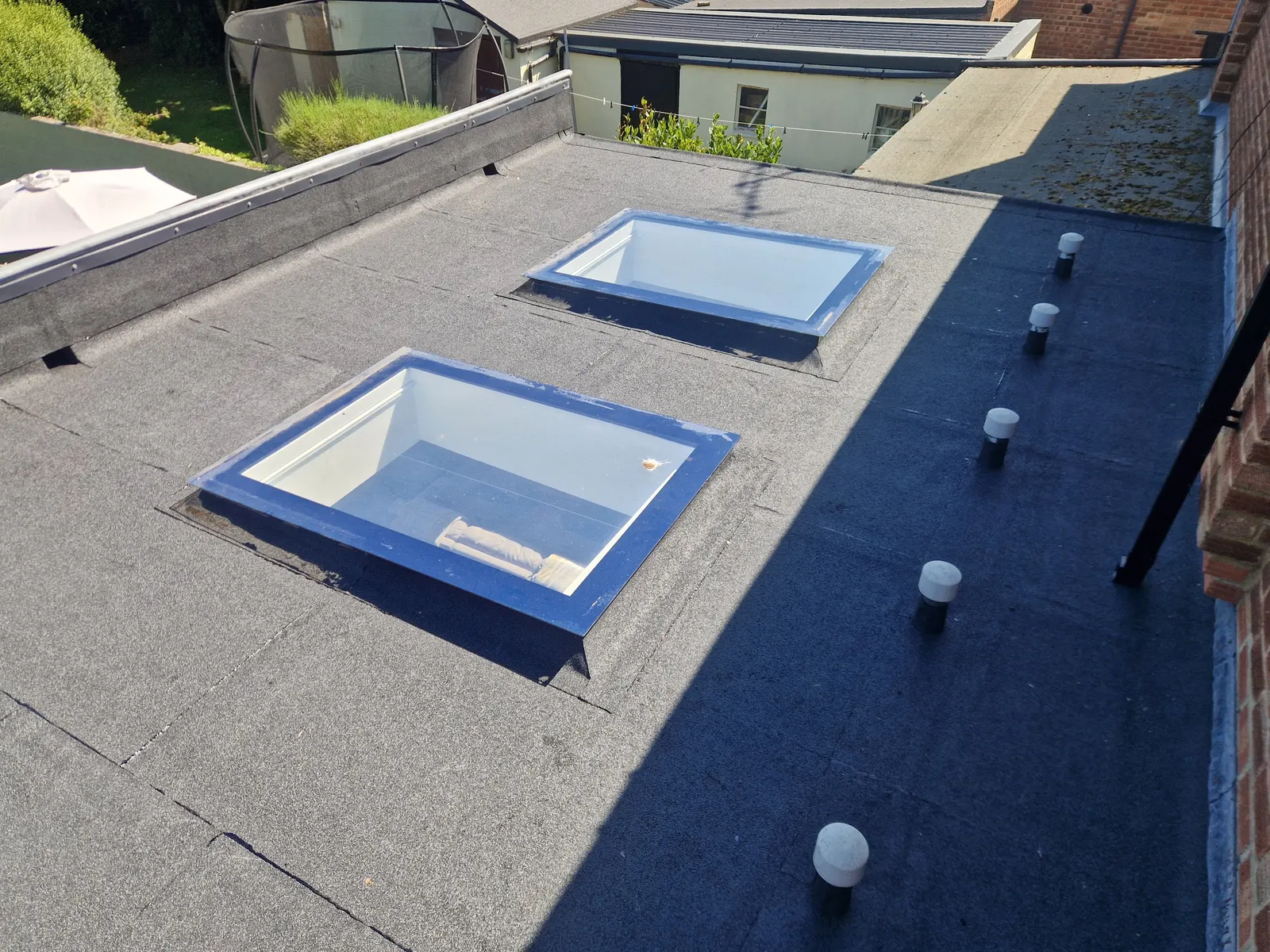 A finished felt flat roof with two roof lights and roof vents