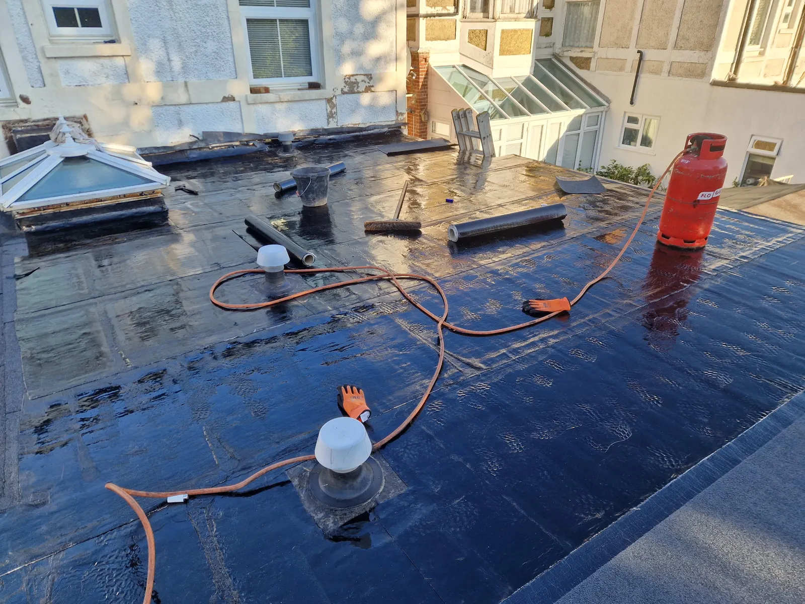 Work in progress by LDR Roofing: torch-on felt being laid on a flat roof with a roof lantern