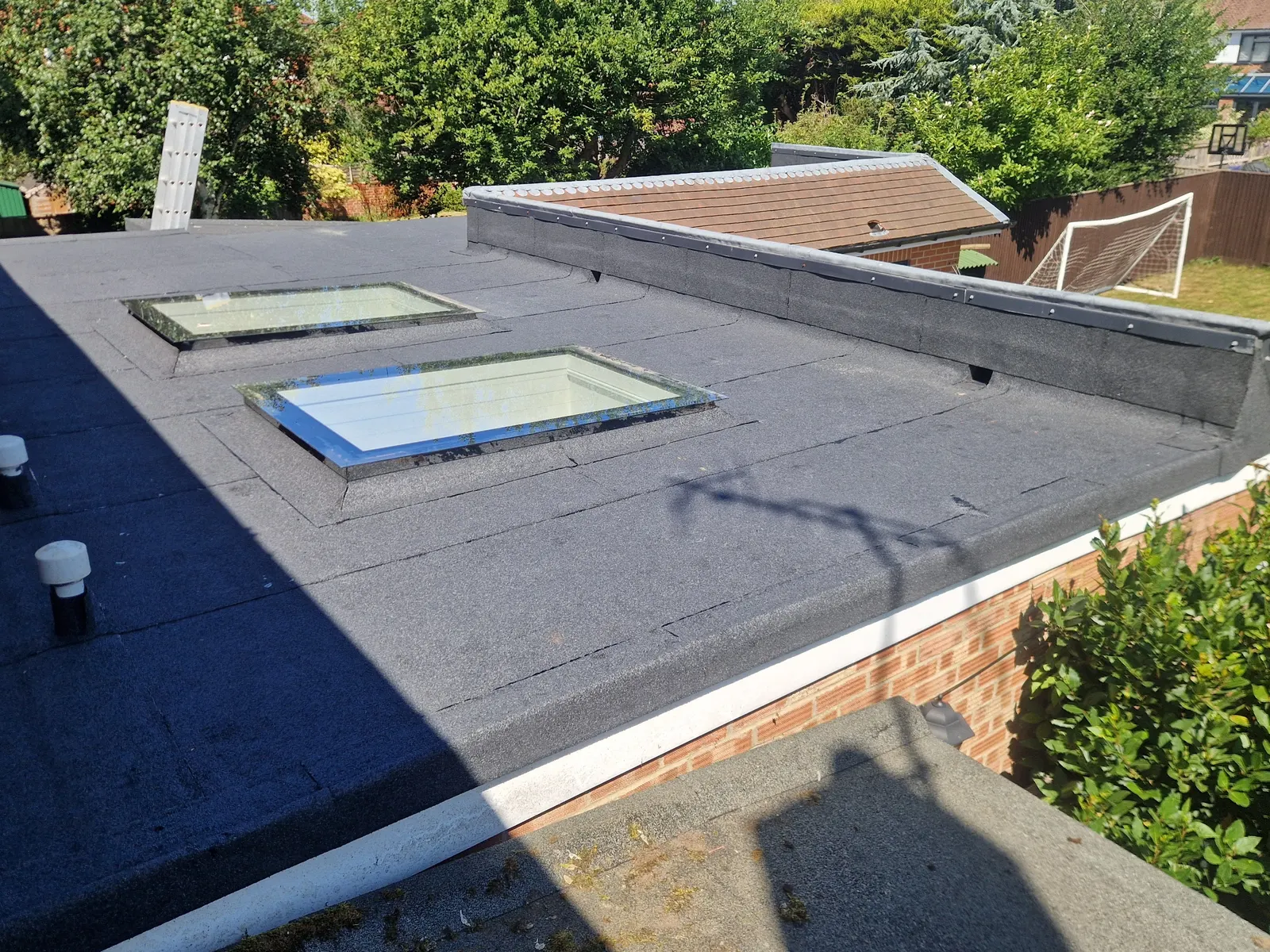 A mineral felt flat roof finished around the kerbs of two roof lights