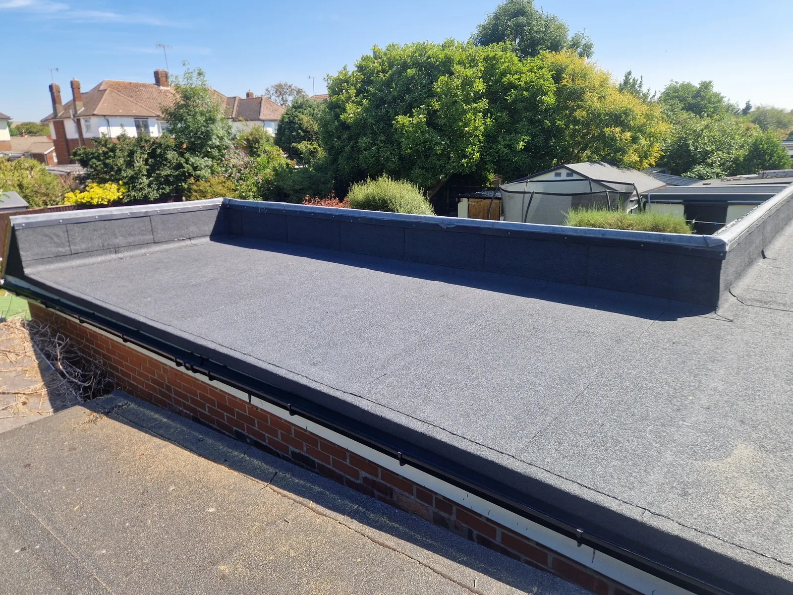 A finished flat roof with felt dressed up and over the raised edges