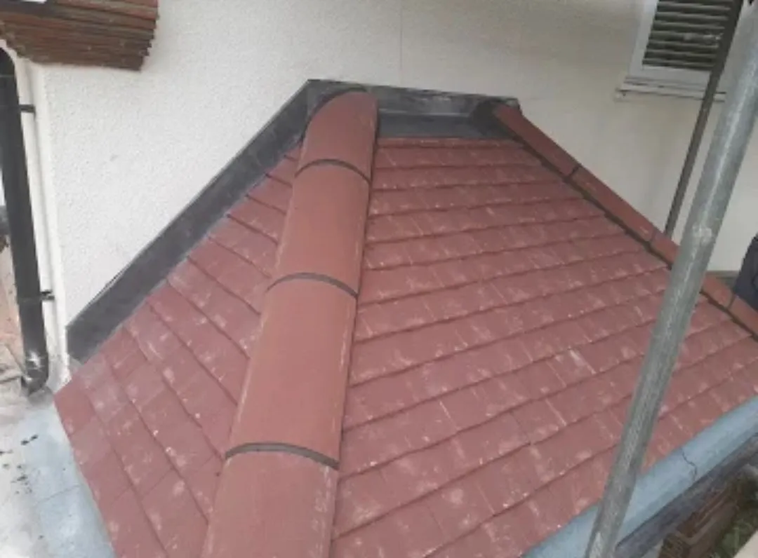 A small tiled hipped roof with lead flashing where it meets the wall